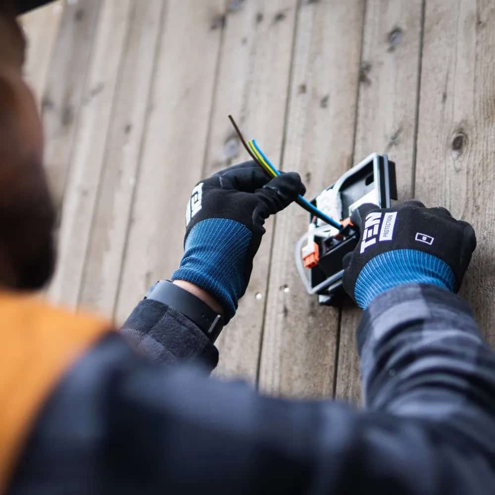 Person sågar träskiva med cirkelsåg och skena. Dammsugare ansluten